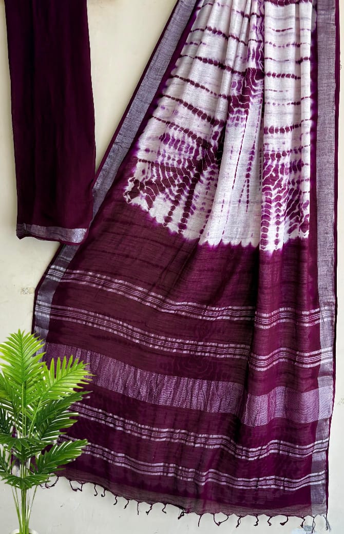 Purple and white patterned fabric draped over a white surface with a plant in the foreground.